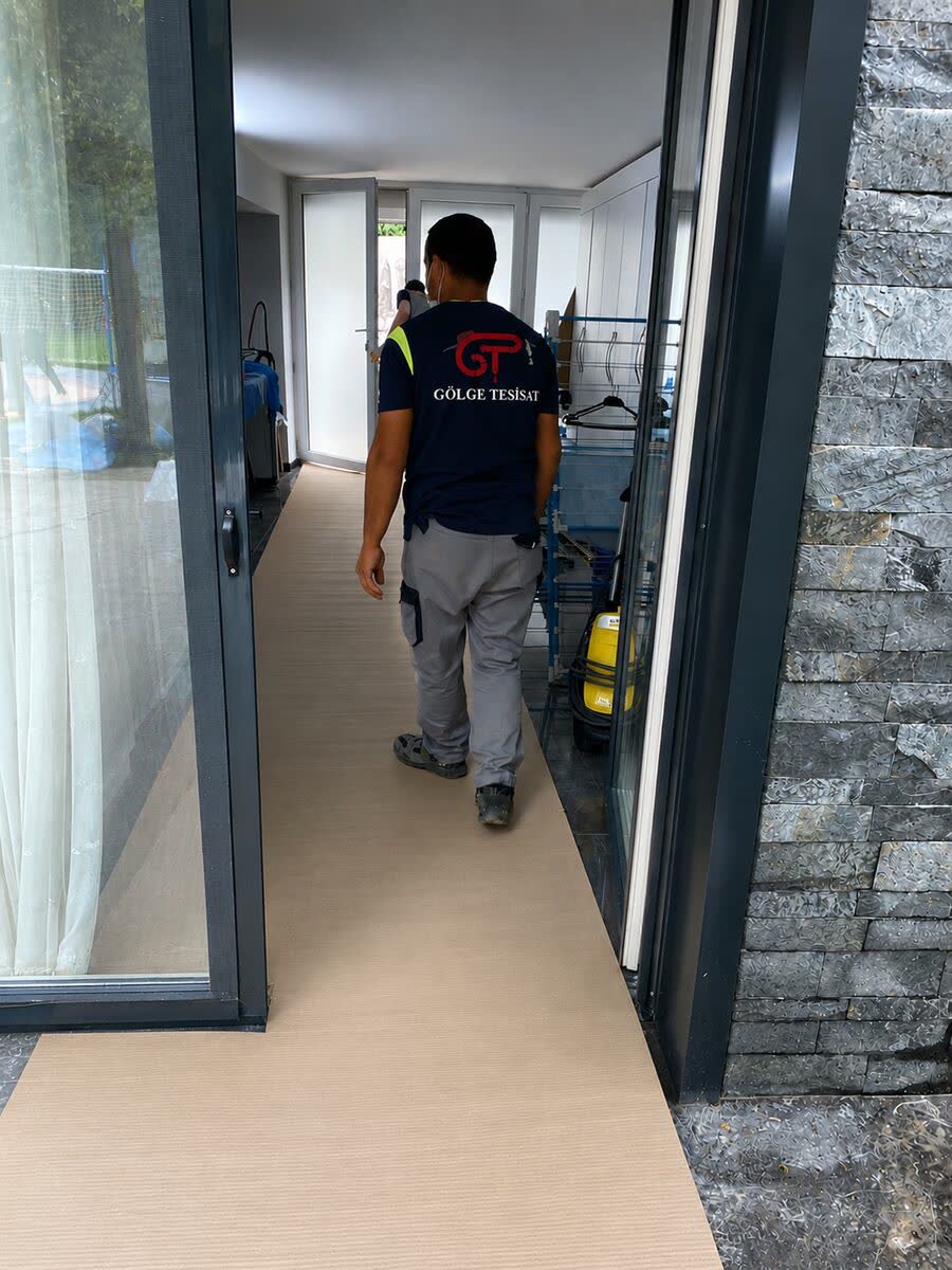 Gölge Tesisat ustası eve girerken yer örtüsü ve ayakkabı koruyucu kullanıyor